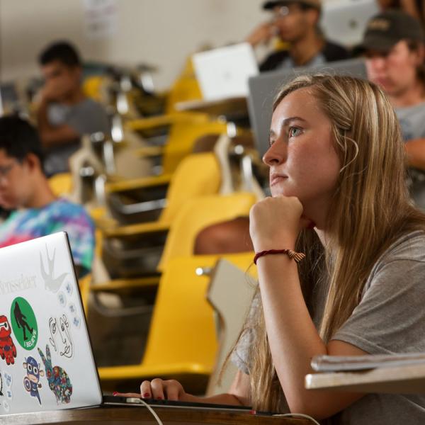 Female student with a laptop listening to a lecture