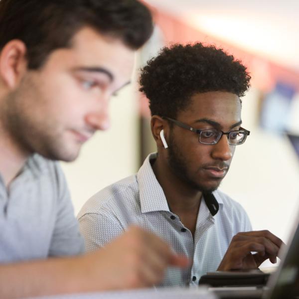 Two students working together on a laptop